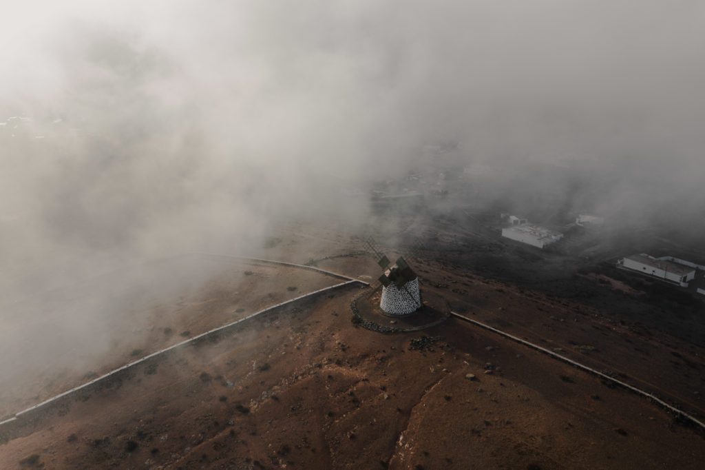 Windmill on desert behind clouds
