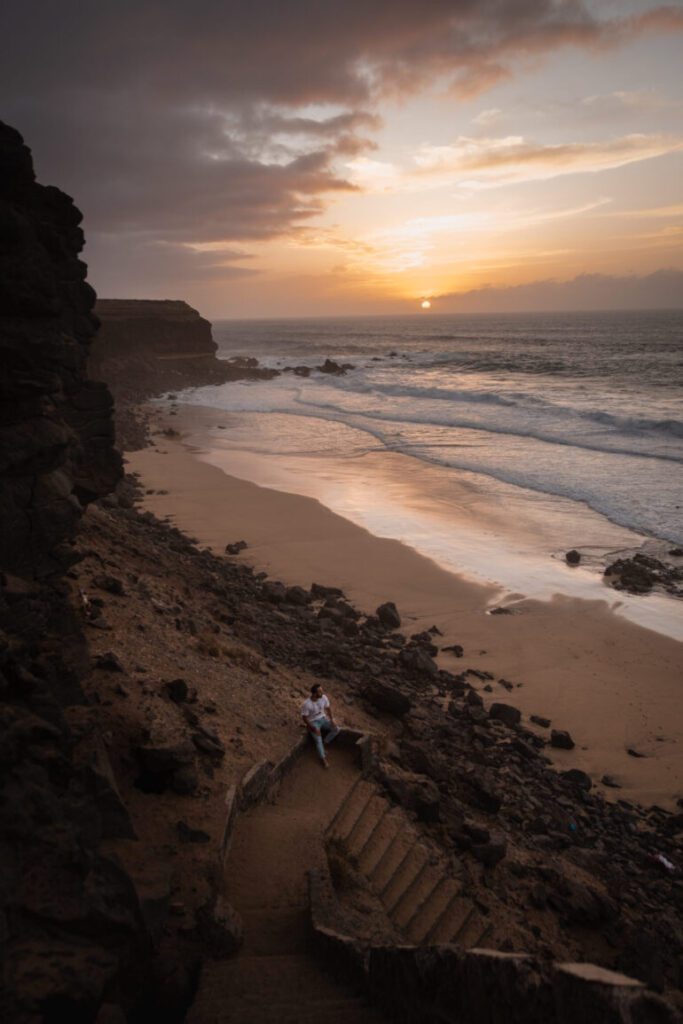 Man sitting on stairs to the beach